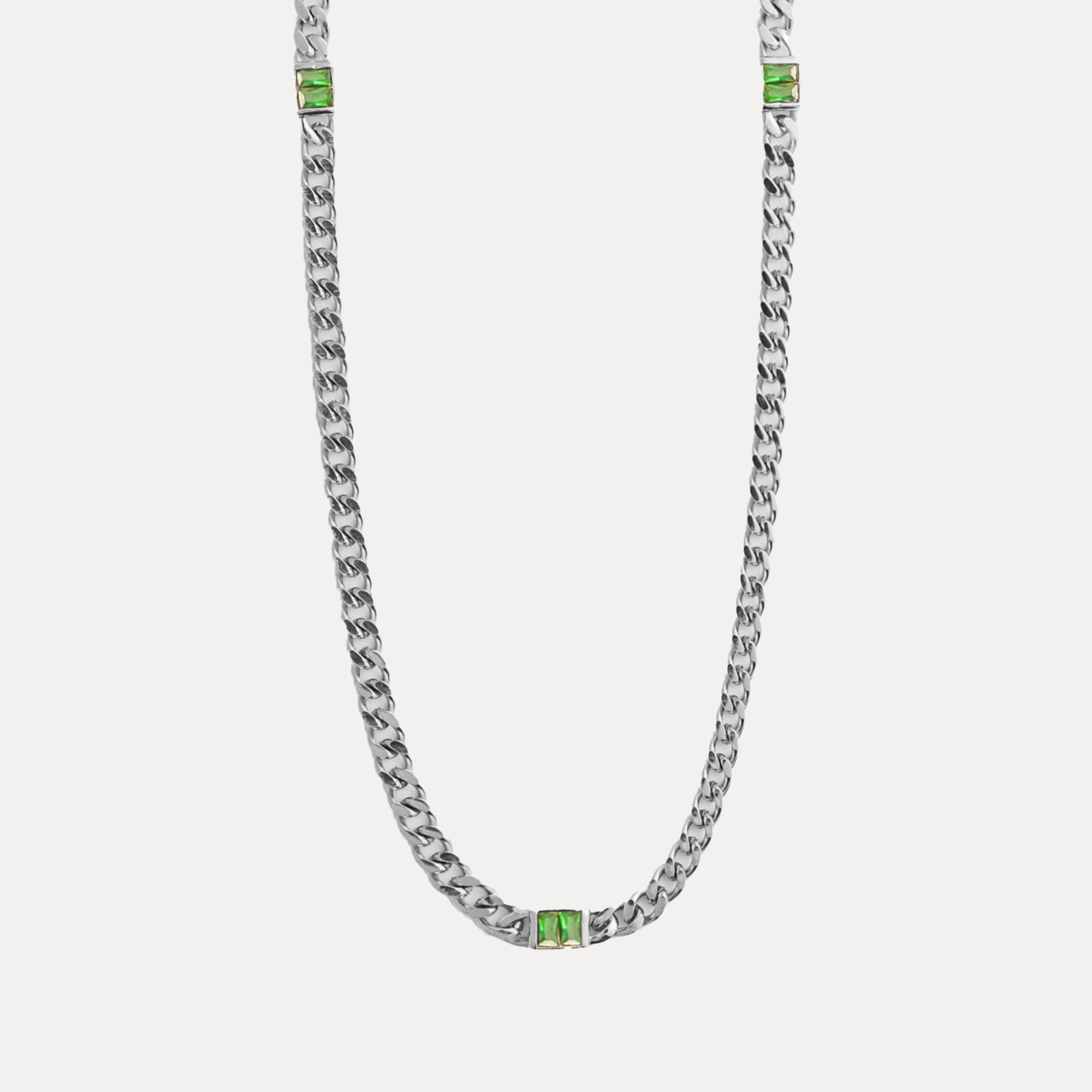 Silver chain necklace with green gemstones on a light gray background