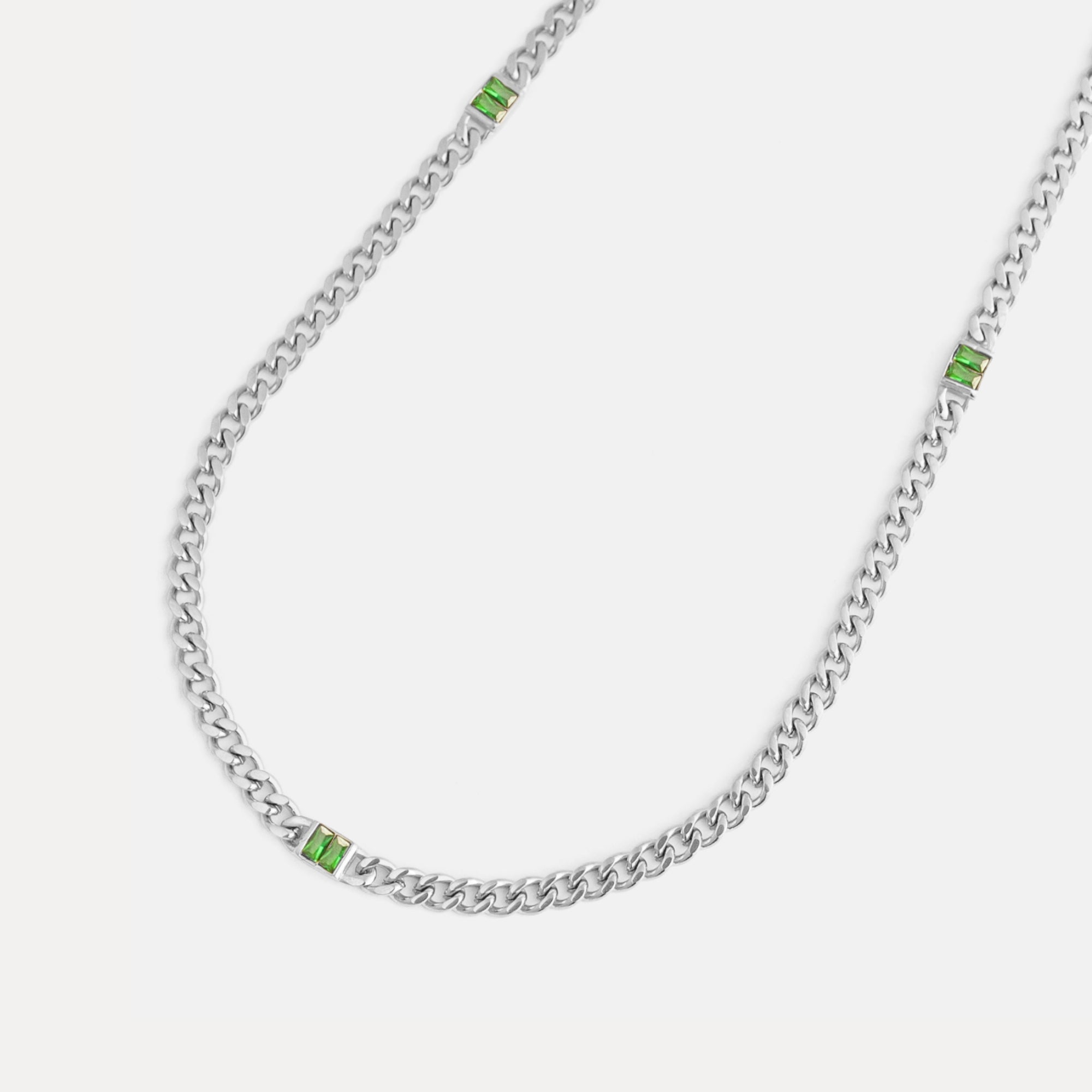 Silver chain necklace with green gemstones on a white background