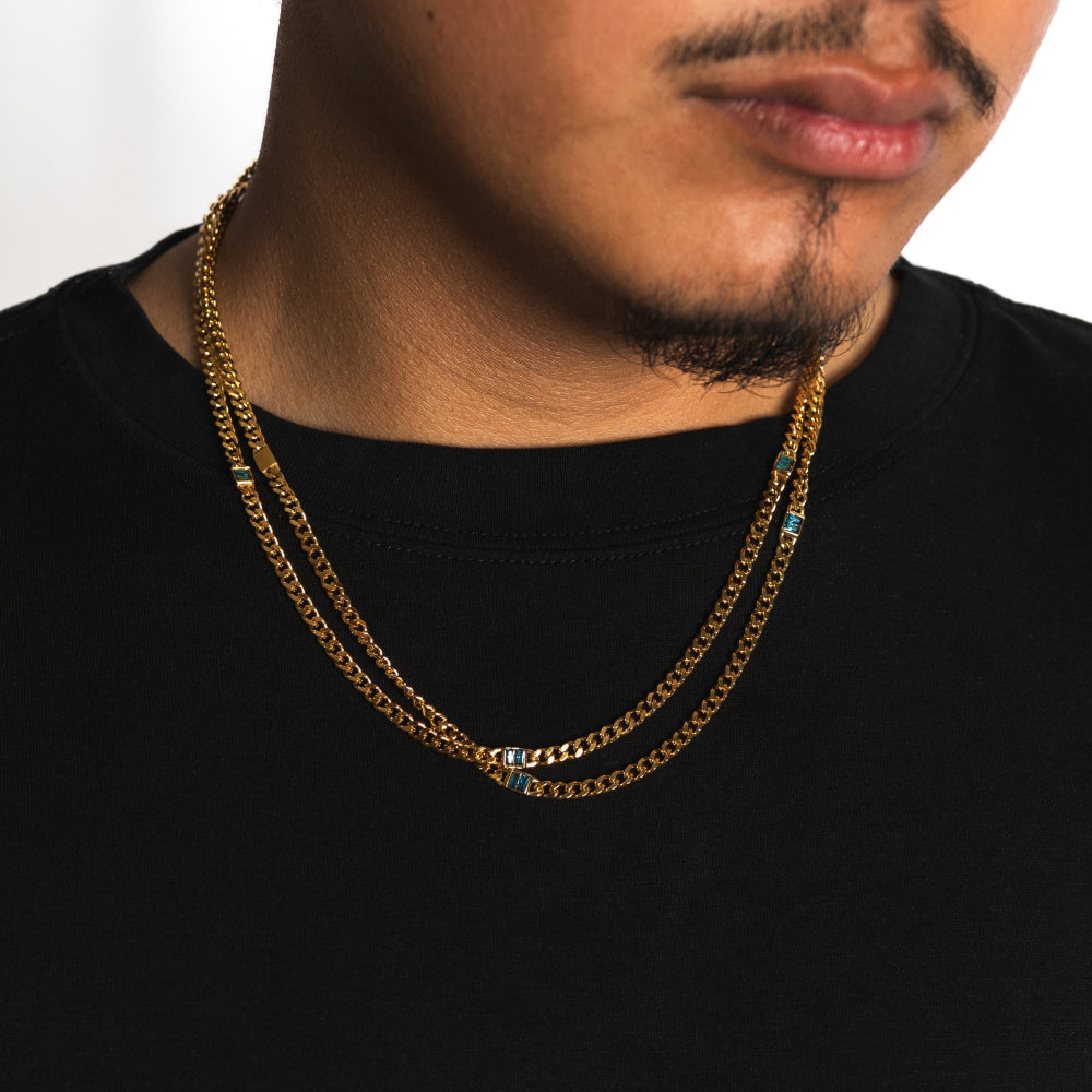 Man wearing a gold chain necklace on a plain background