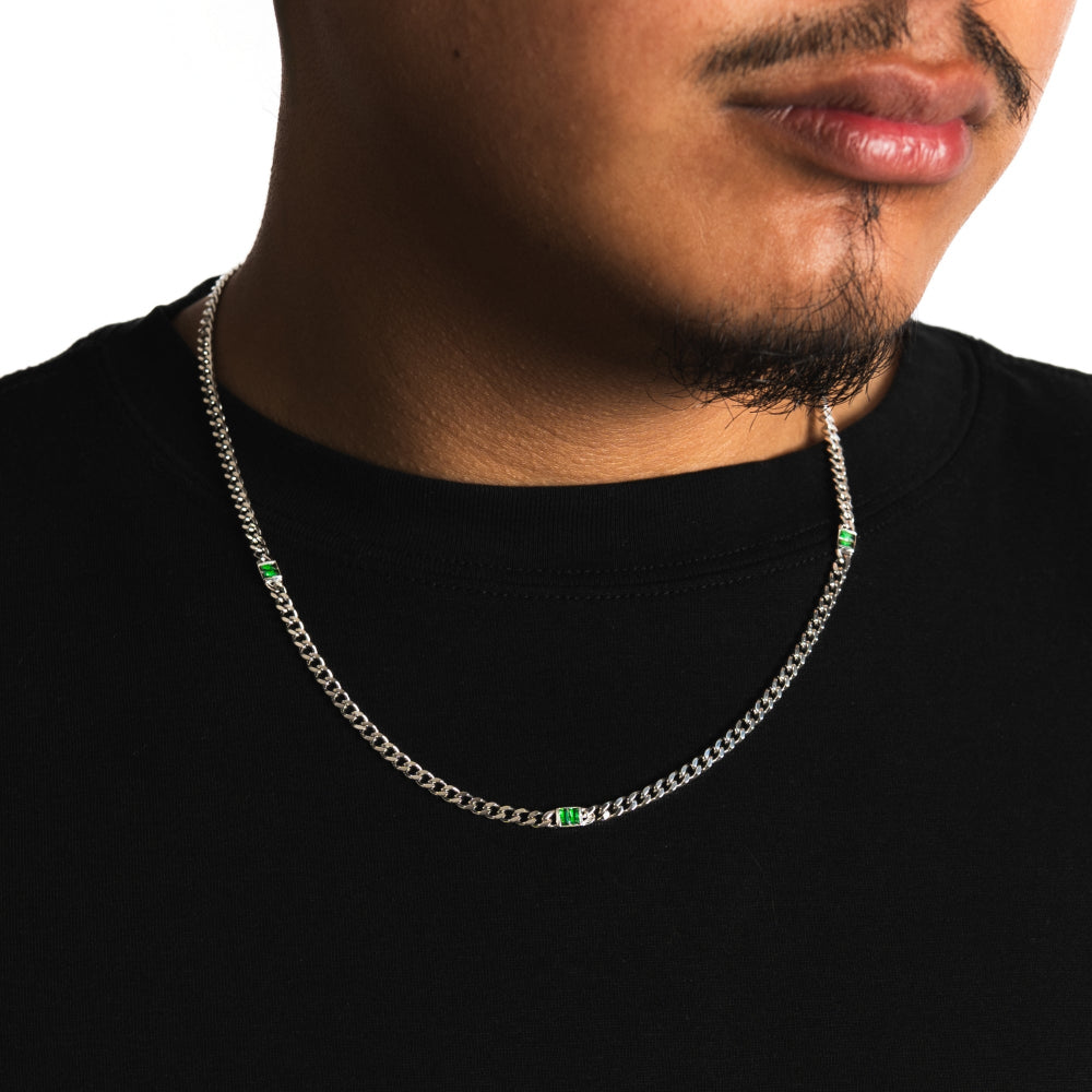 Man wearing a silver chain necklace with green beads on a black background