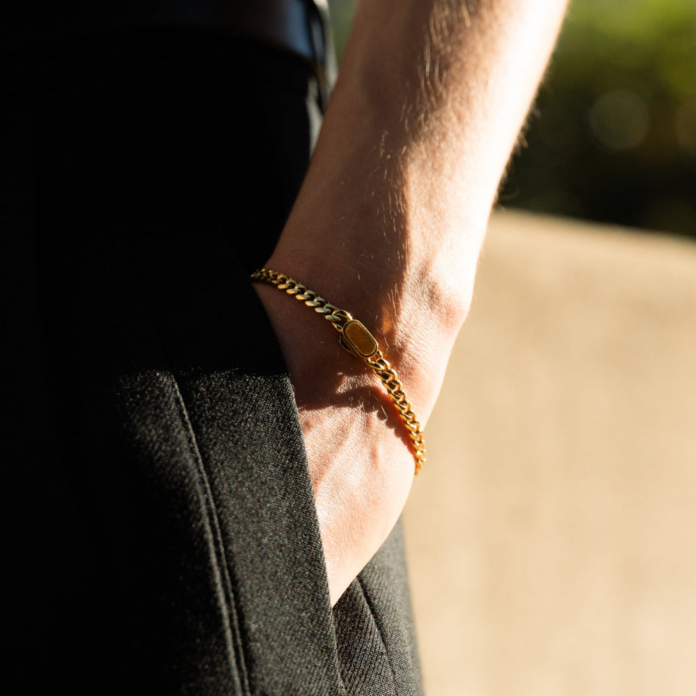 Gold chain bracelet on a wrist with a blurred background