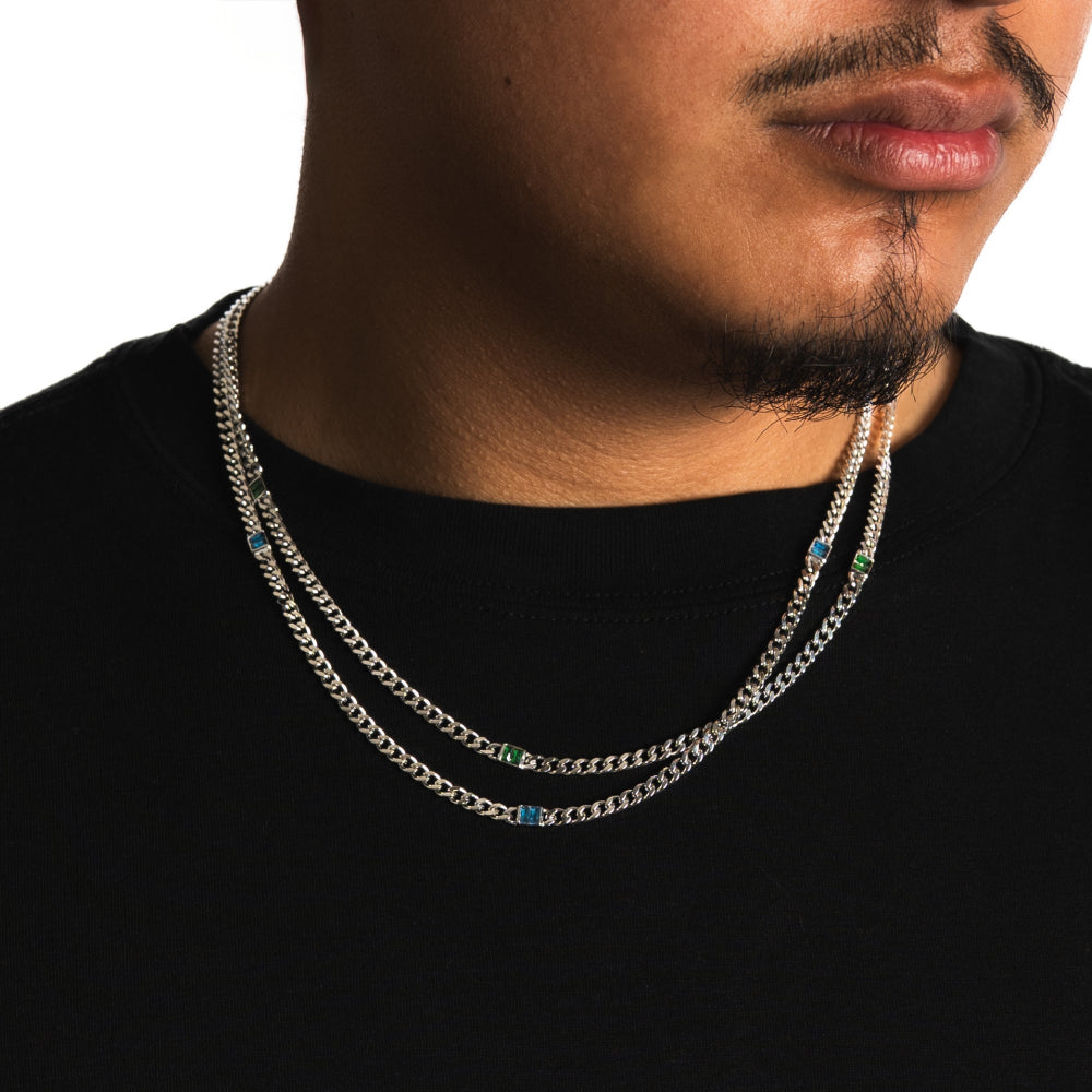 Man wearing a silver chain necklace with small stones on a plain background