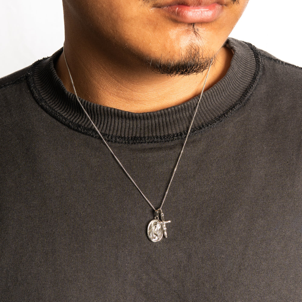 Person wearing a black sweater with a necklace featuring a pendant.