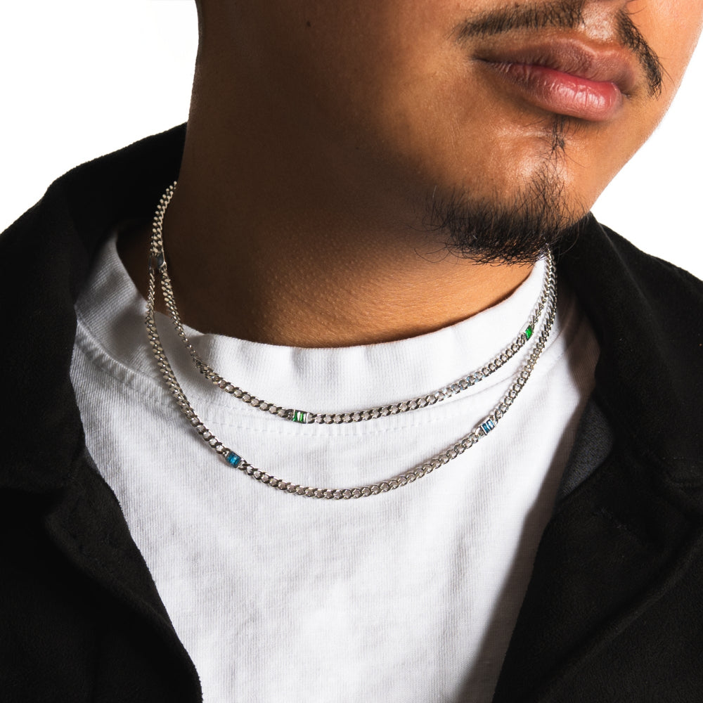 Close-up of a person wearing multiple silver chain necklaces on a white background