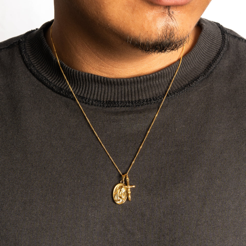 Person wearing a black sweater with a gold necklace featuring a pendant.