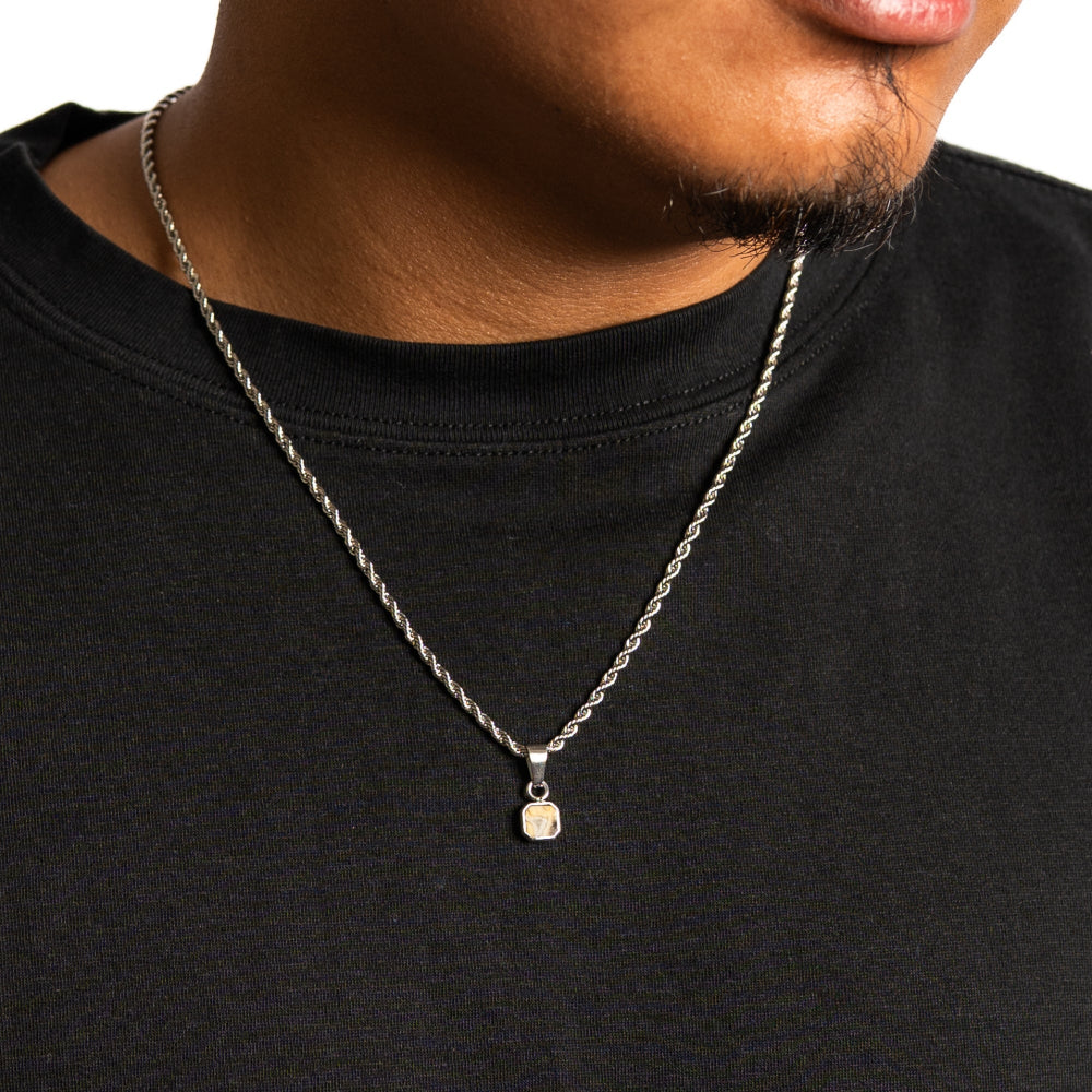 Person wearing a black shirt with a silver necklace featuring a pendant.