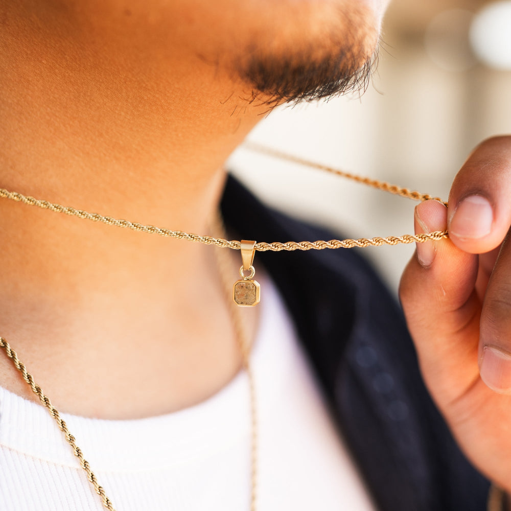 Close-up of a person wearing a gold necklace with a pendant.