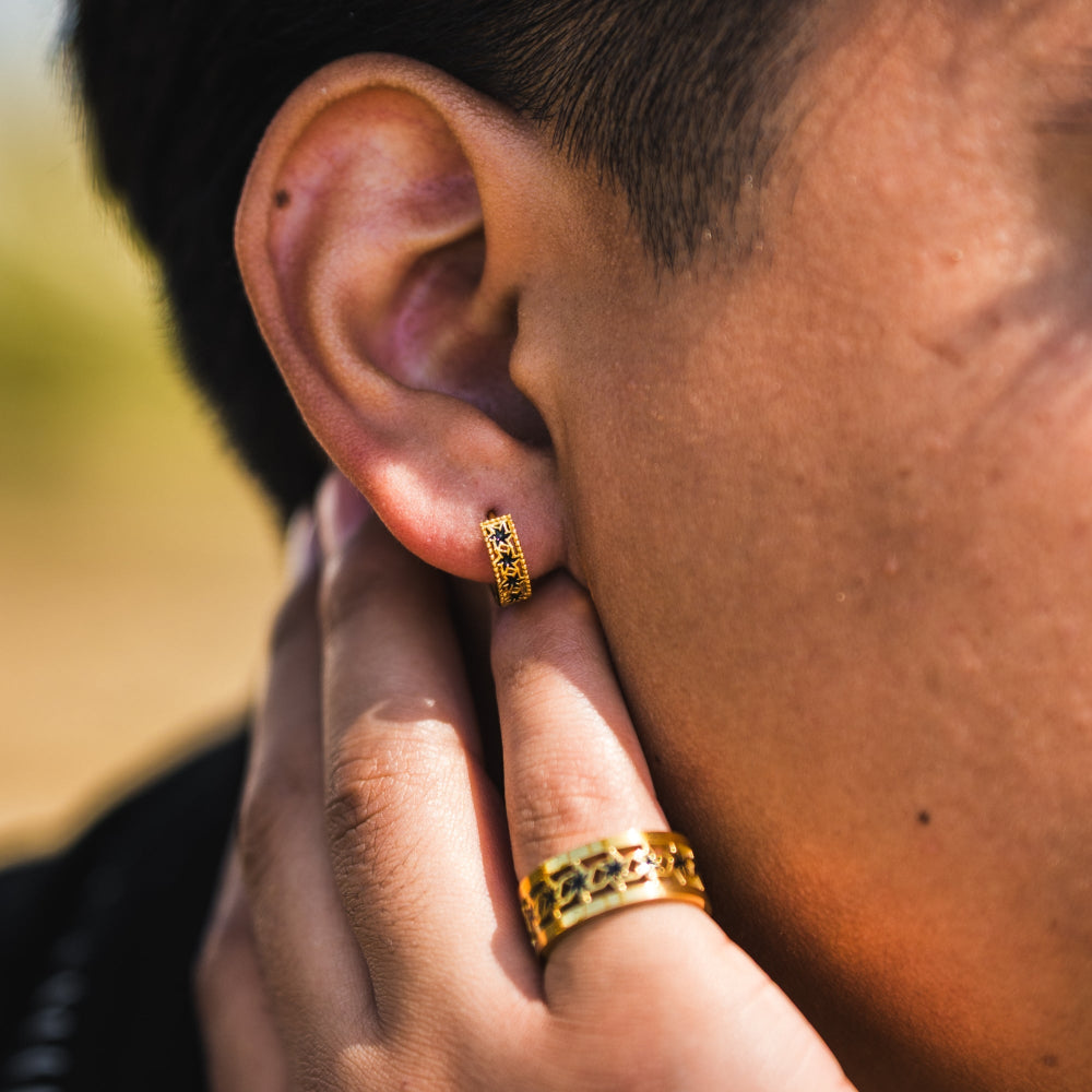 Close-up of an ear with a gold hoop earring and matching ring.