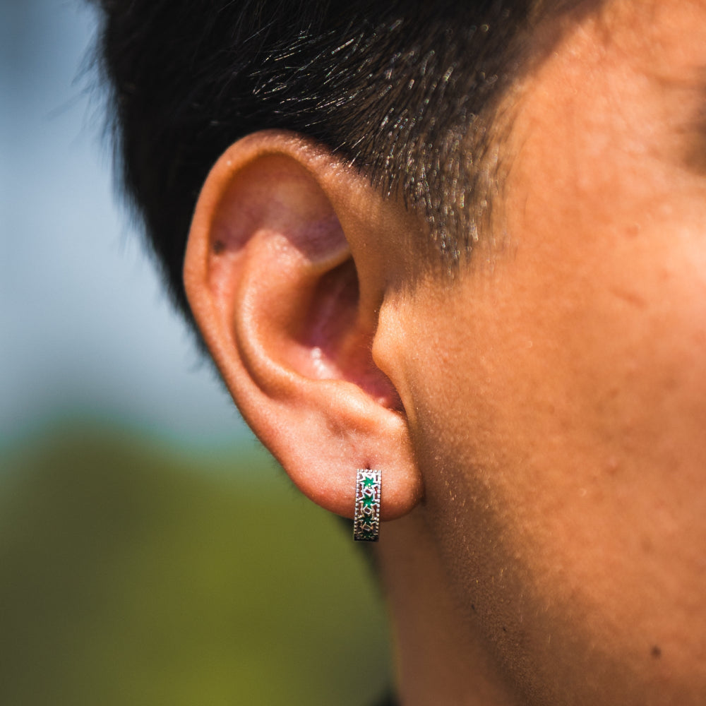 Close-up of an ear wearing a green gemstone earring with a blurred background