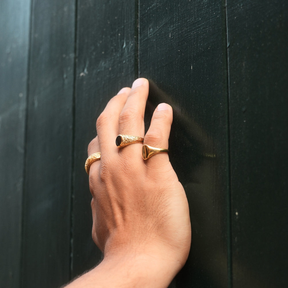 Hand wearing gold rings on a dark wooden background