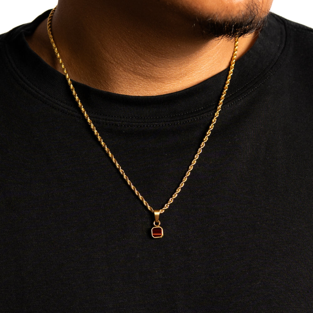 Gold chain necklace with a pendant on a black shirt