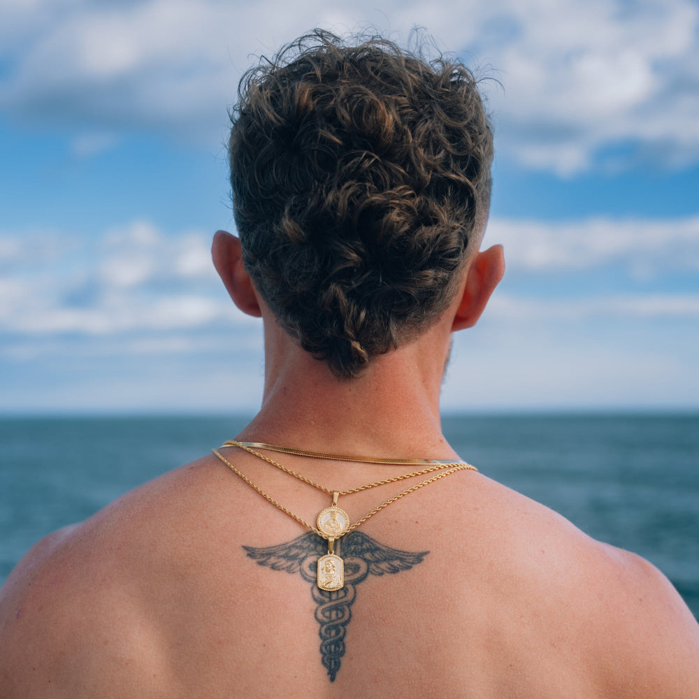 Person with braided hair and tattoo on shoulder looking at ocean