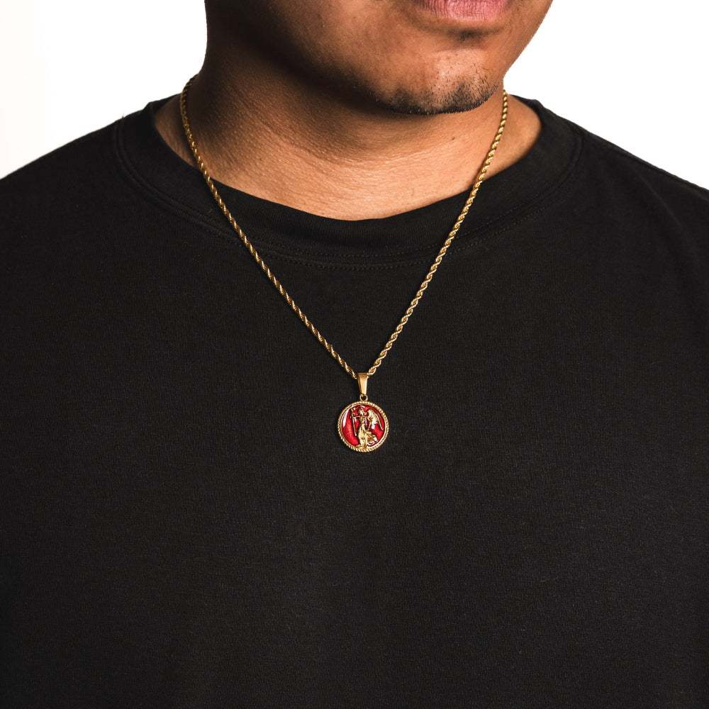 Gold necklace with a red pendant worn by a person on a black background