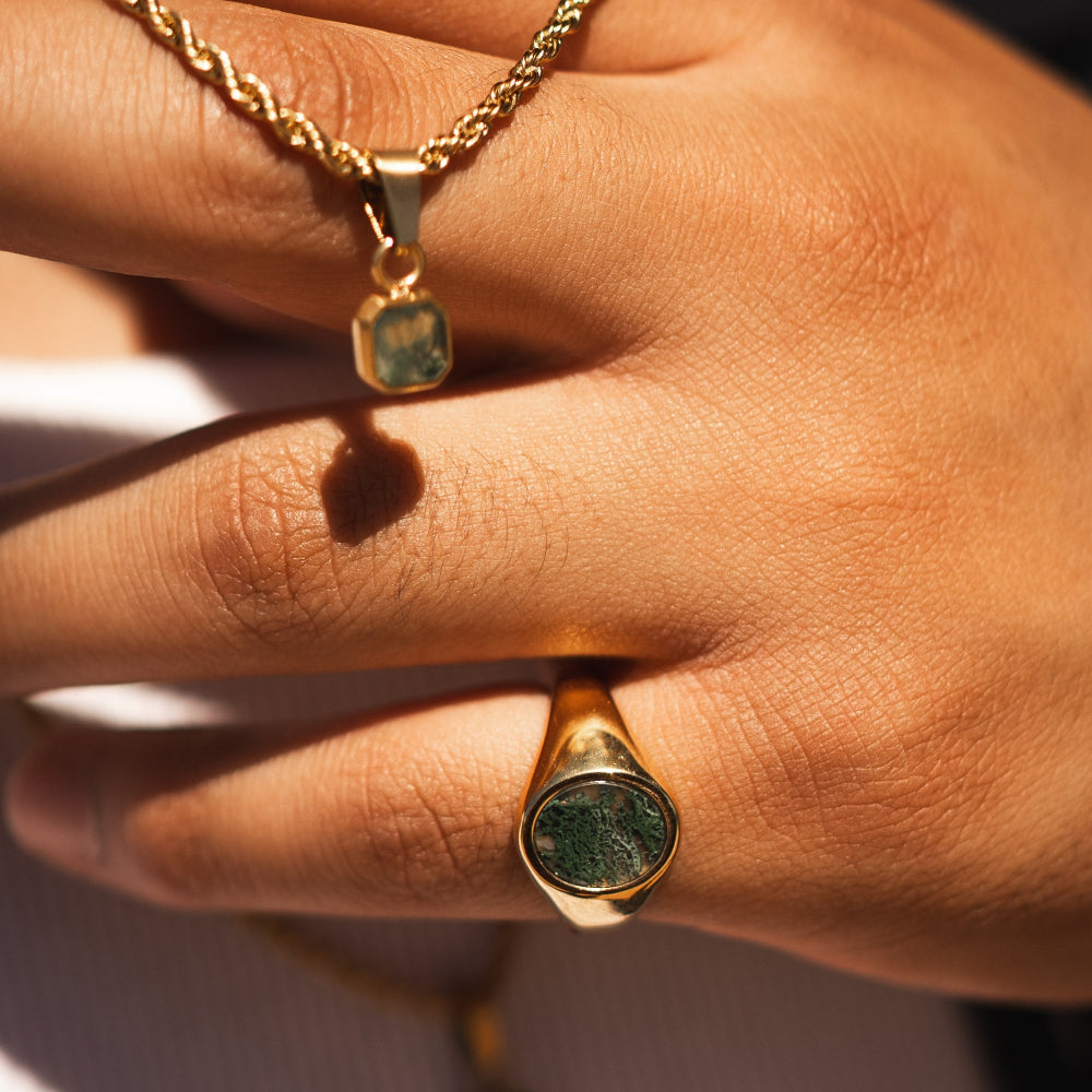 Gold ring with green gemstone on a hand