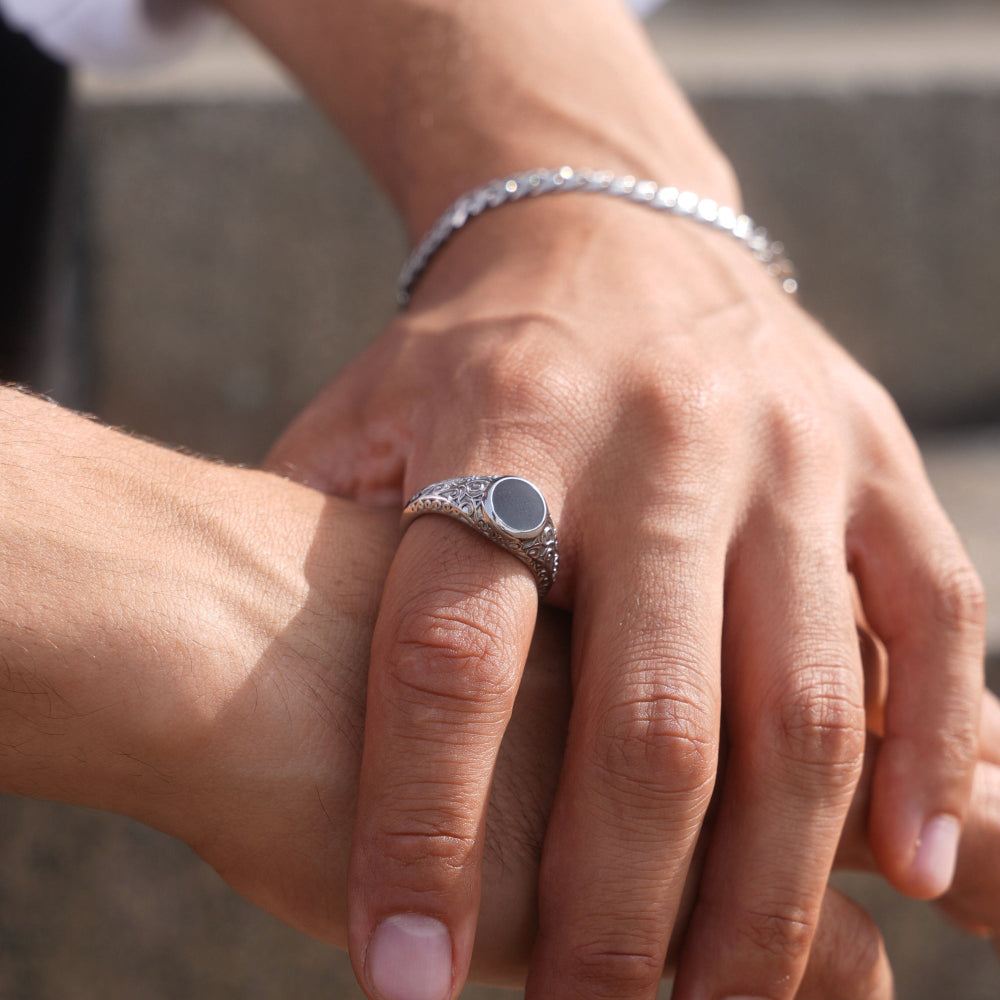 Close-up of two hands holding each other with a silver ring on one finger.