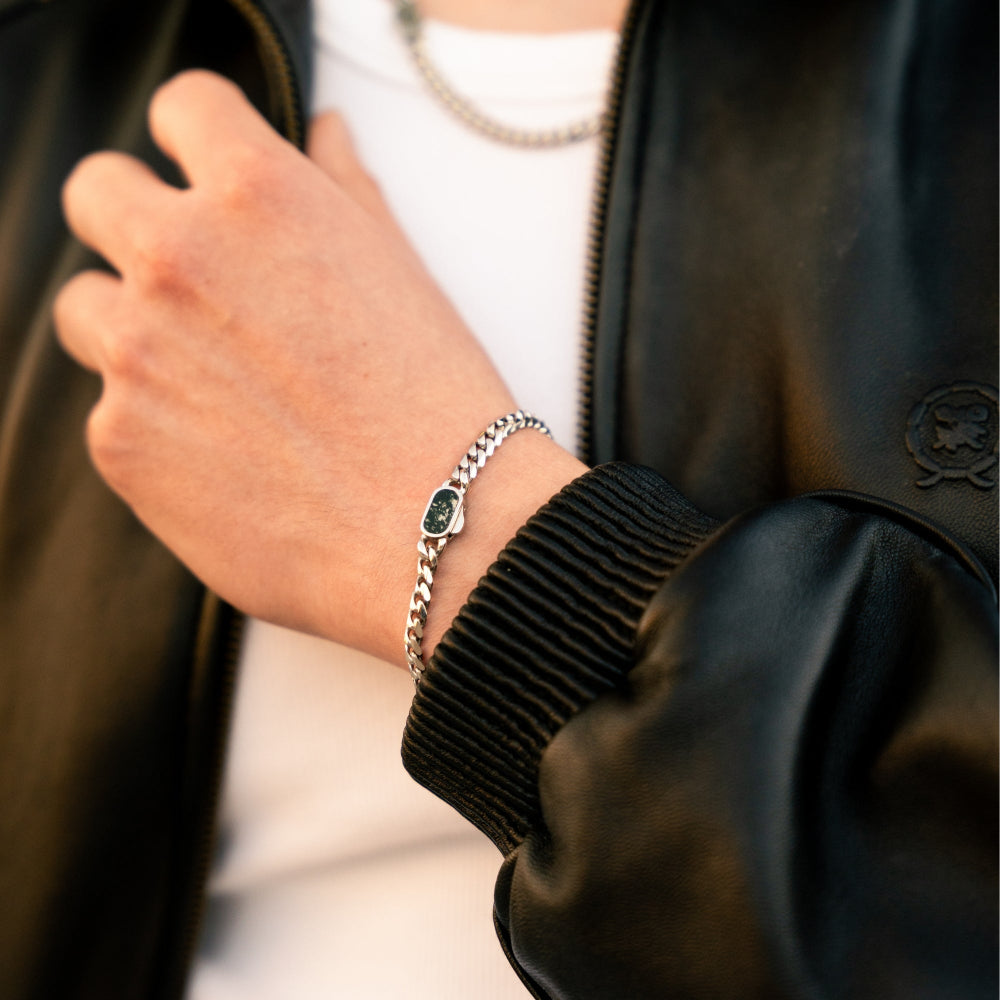Close-up of a person wearing a bracelet with a green stone on a blurred background