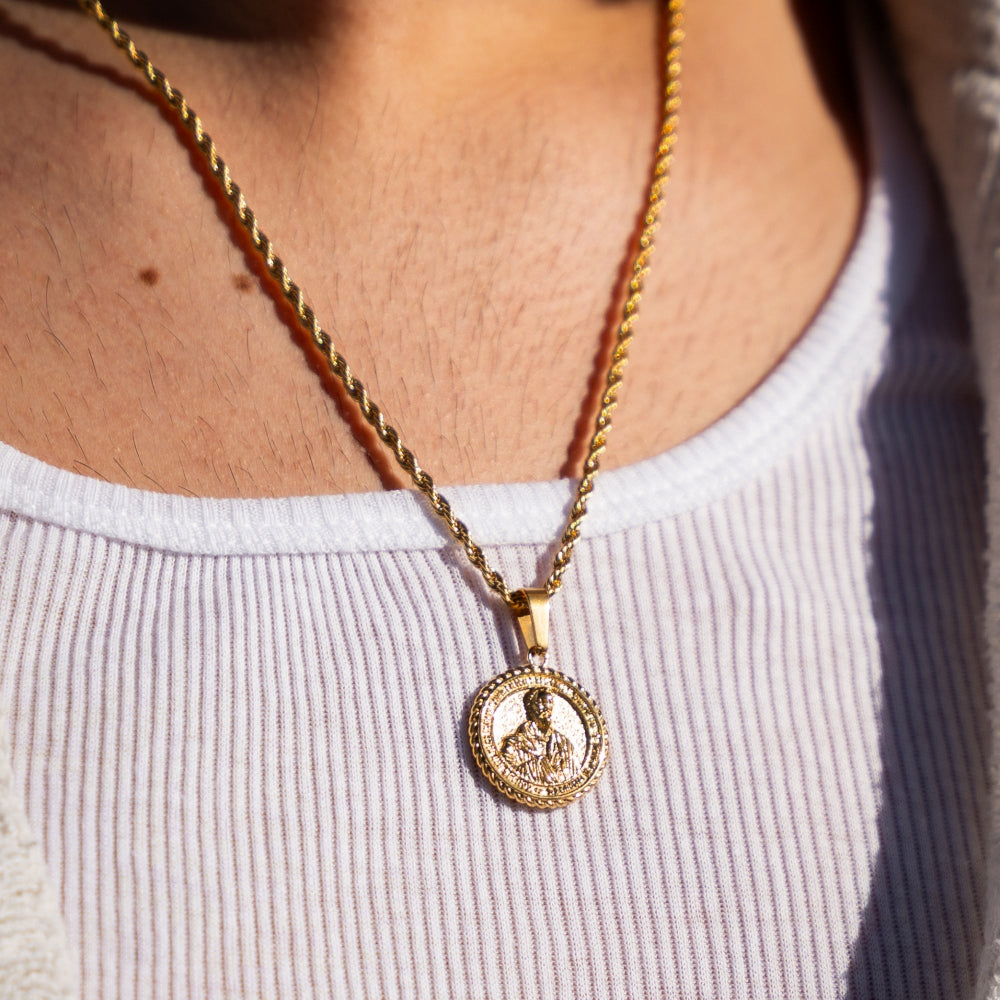 Gold necklace with a pendant worn by a person against a neutral background