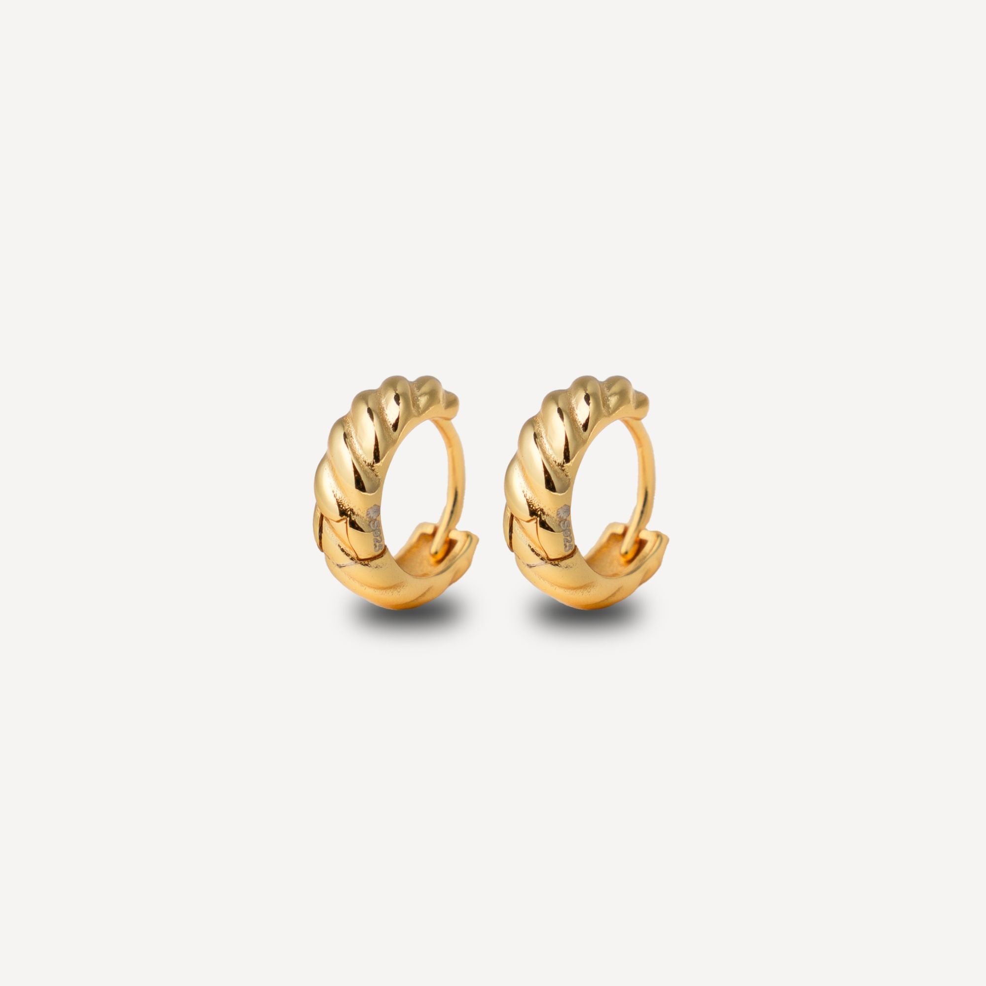 A pair of gold huggie hoop earrings with a textured, twisted rope-like design, displayed on a clean light gray background.