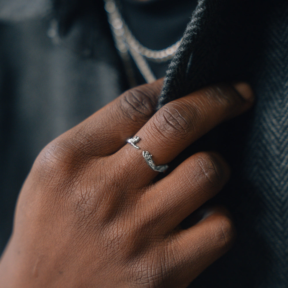 Hand wearing a silver ring with a dark background