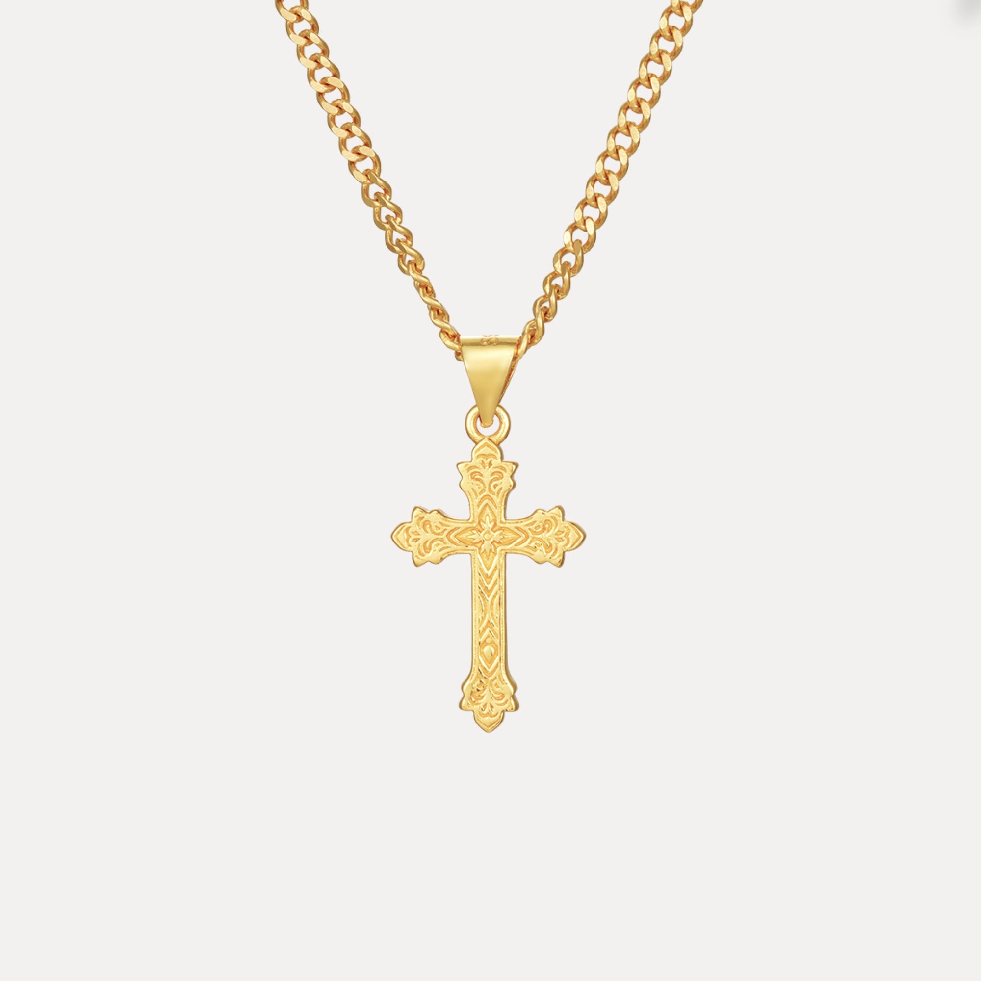 Gold cross necklace on a light gray background