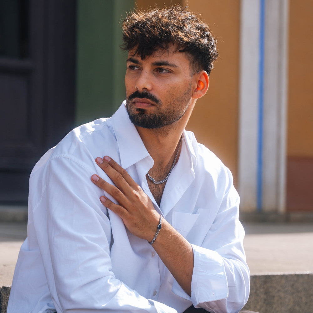 Man in a white shirt sitting outdoors with a blurred background