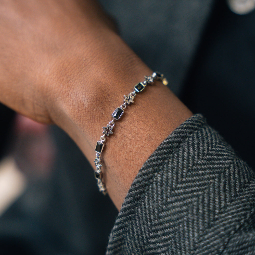 Close-up of a person's wrist wearing a silver bracelet with dark beads.