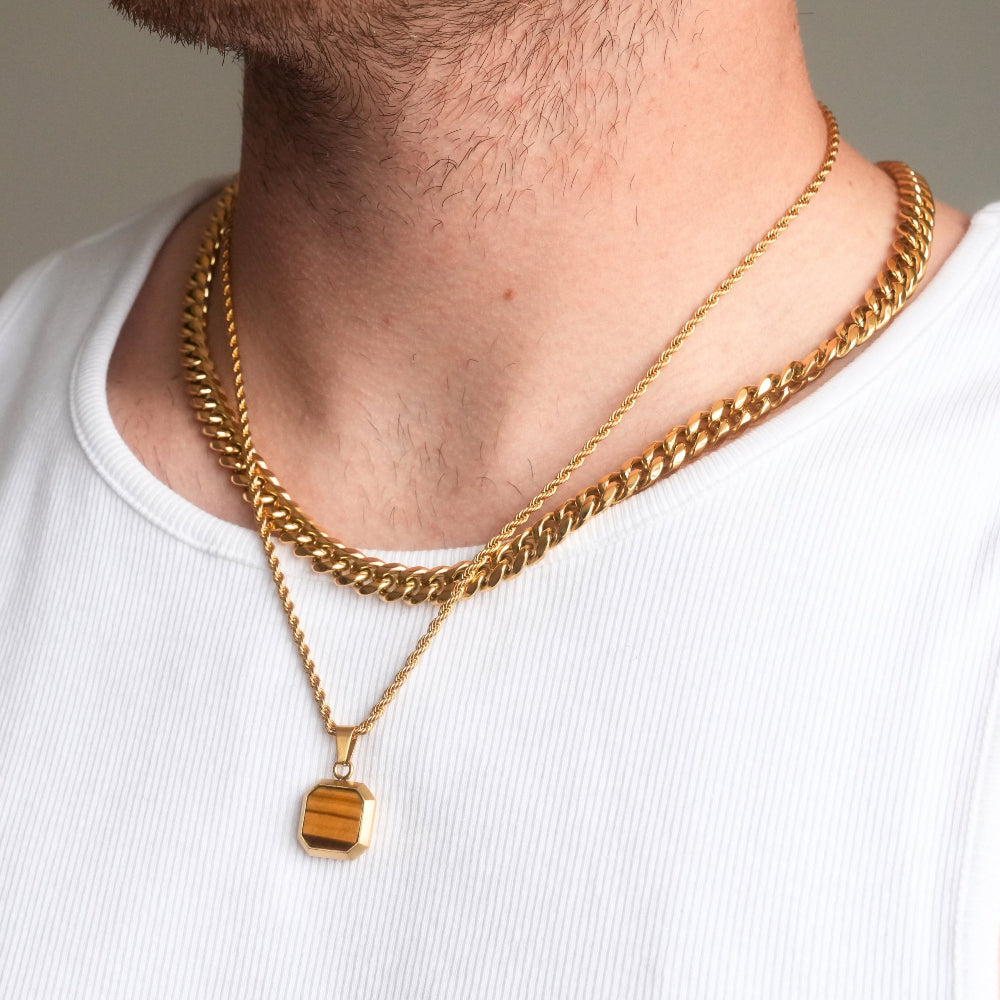 Gold chain necklaces on a person wearing a white shirt