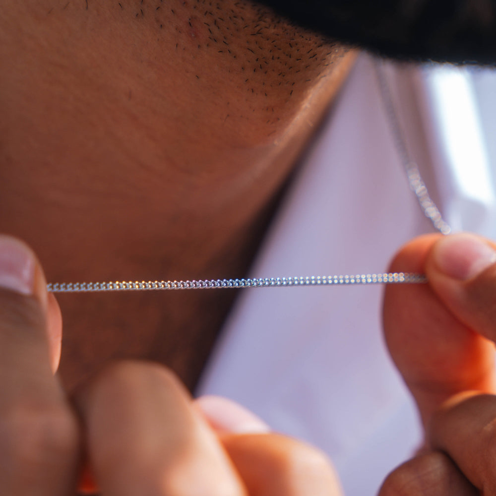Close-up of a person holding a thin metal chain.