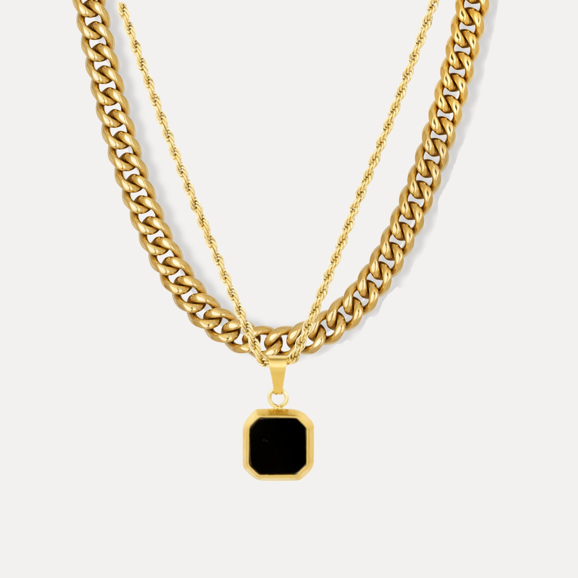 Gold chain necklace with a black pendant on a white background