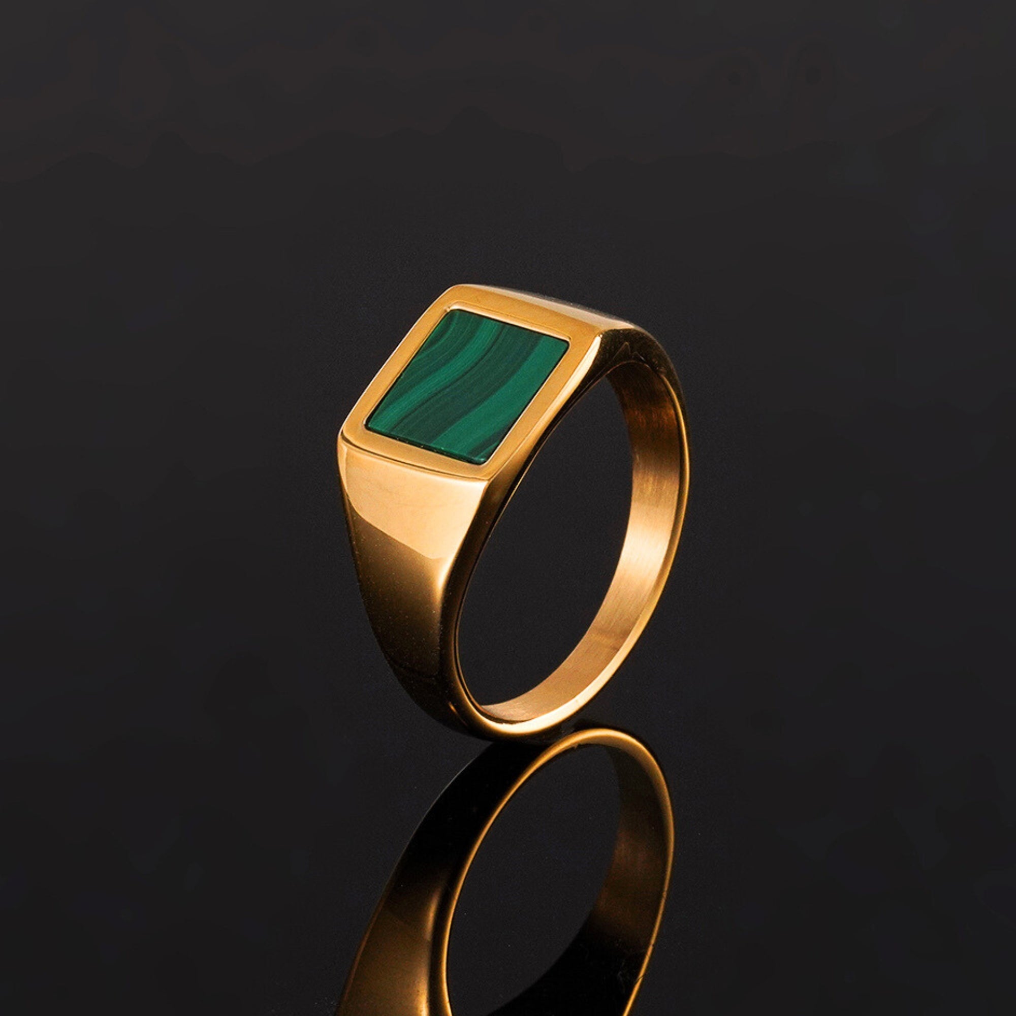 Gold ring with a green stone on a black background