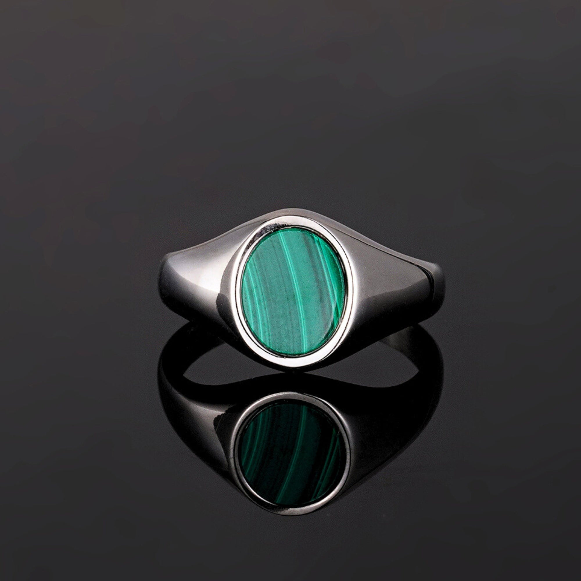 Silver ring with a green stone on a black background