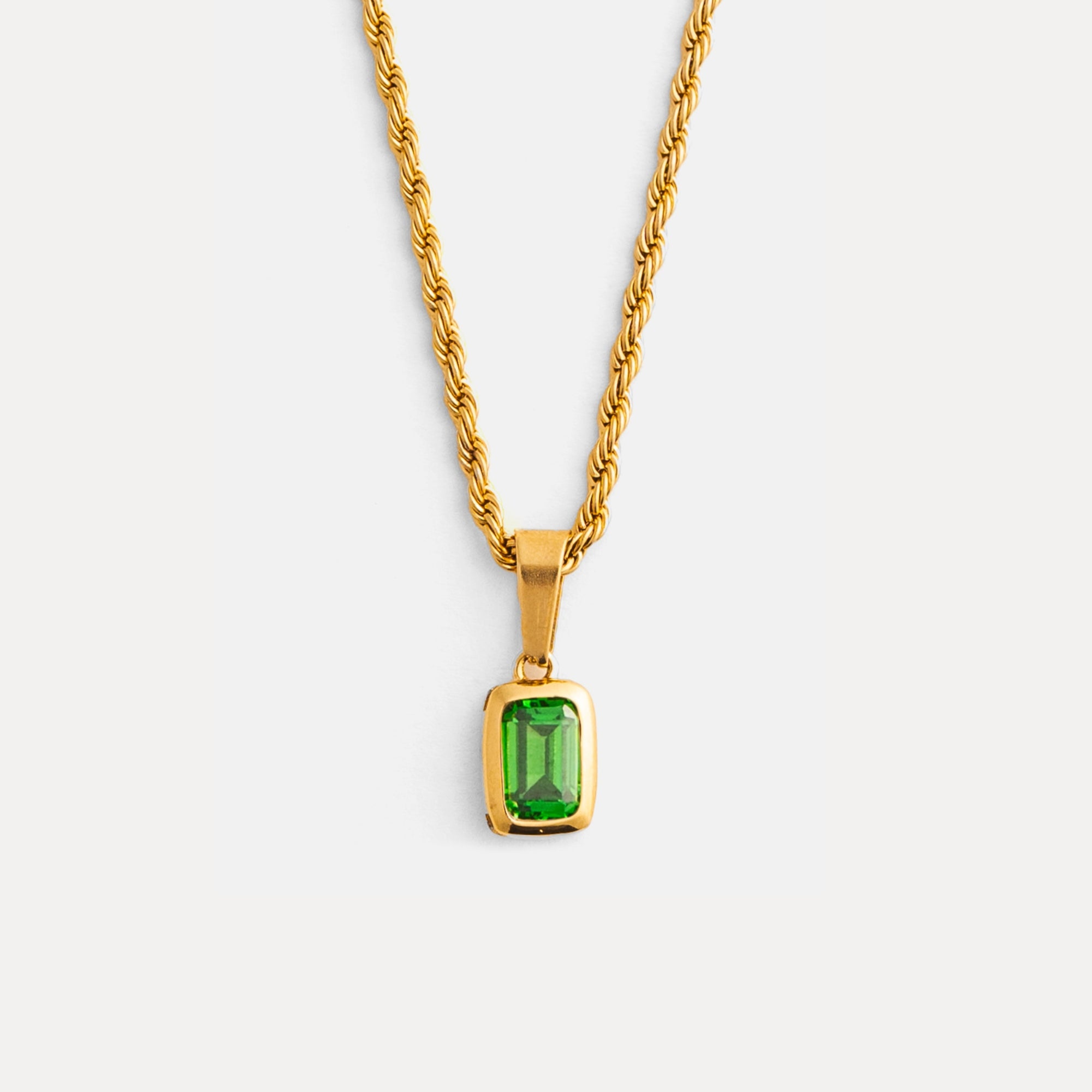 Gold necklace with a green gemstone pendant on a white background