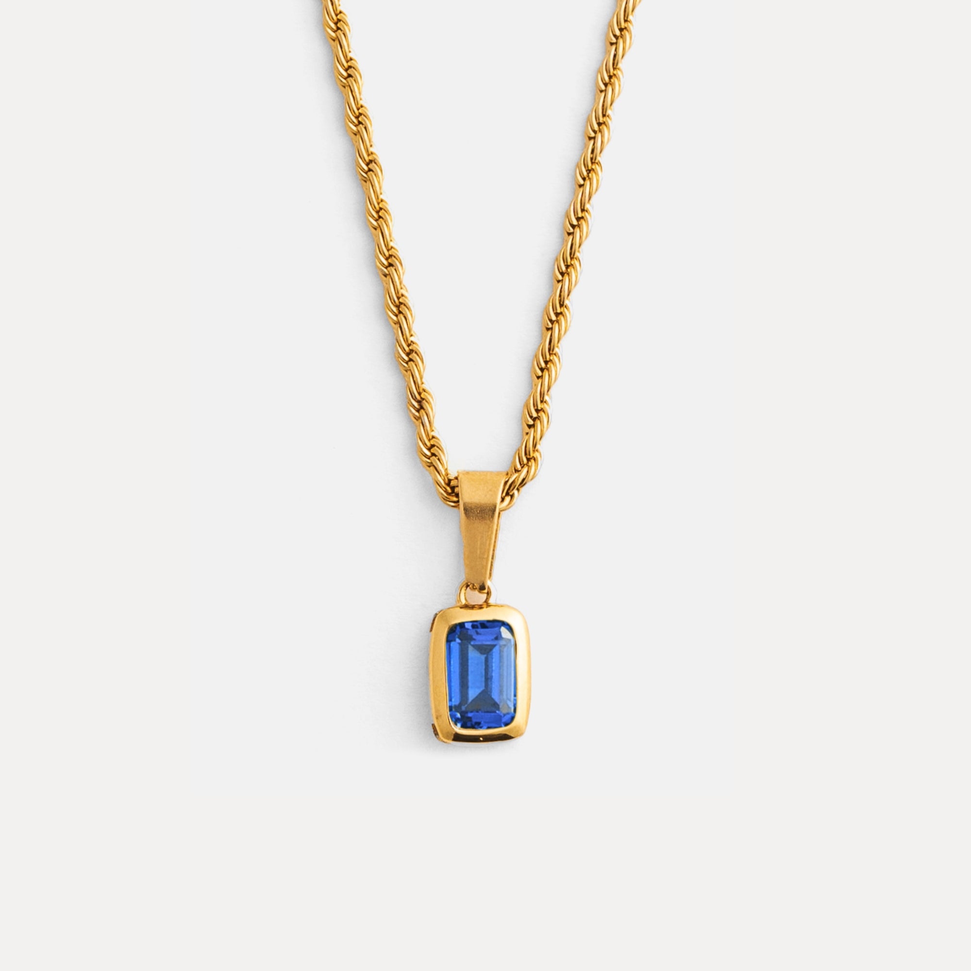 Gold necklace with a blue gemstone pendant on a white background