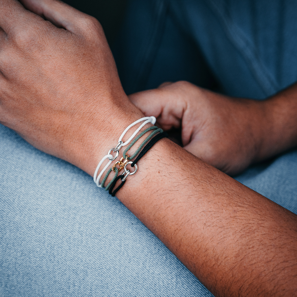 Close-up of a person's wrist wearing multiple bracelets on a blue fabric background