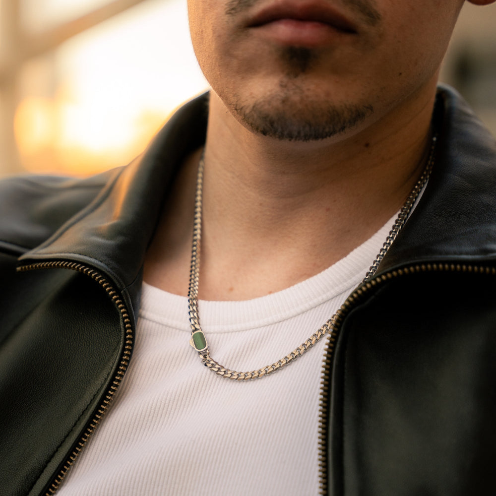 Person wearing a black leather jacket and white shirt with a chain necklace.