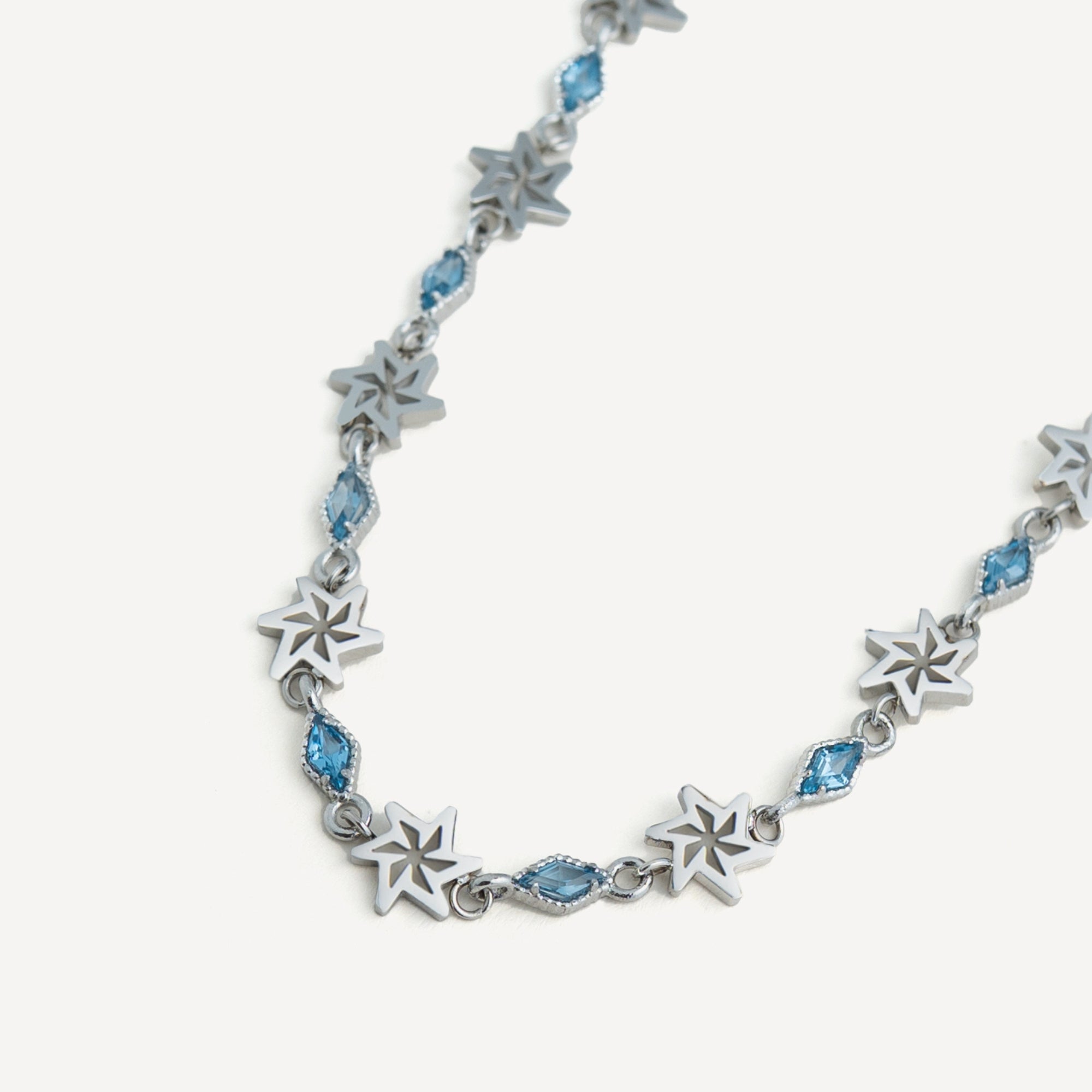 Silver star-shaped necklace with blue gemstones on a white background
