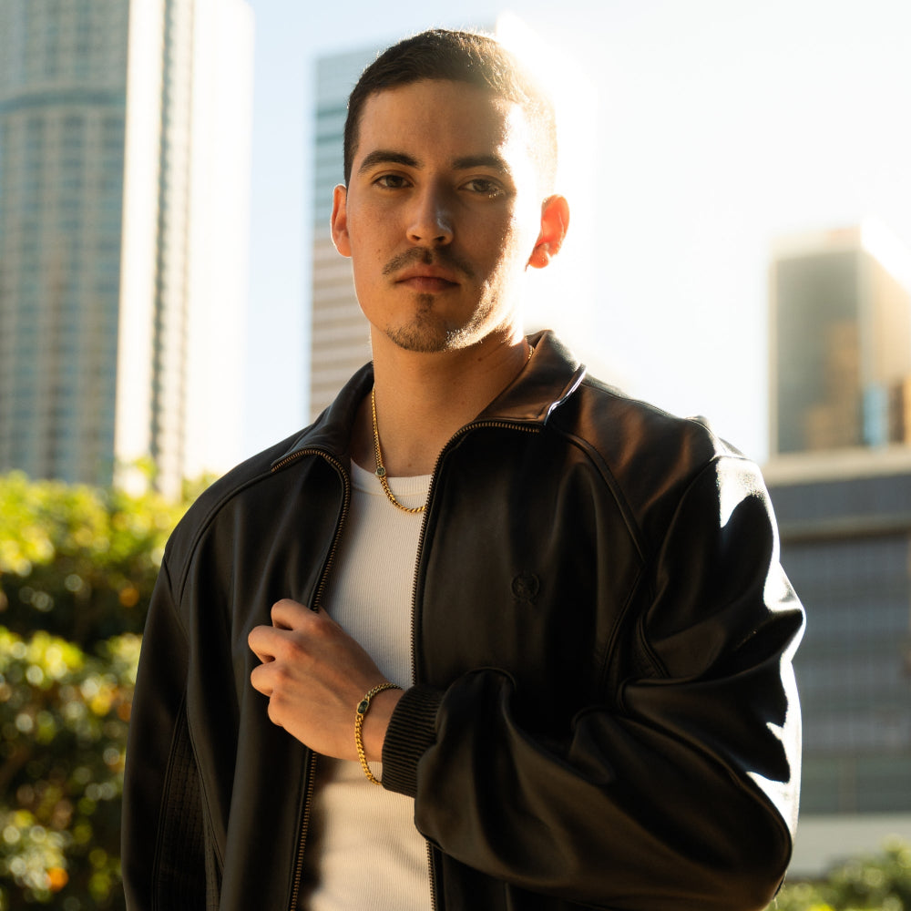 Man wearing a dark jacket and white shirt with a cityscape background