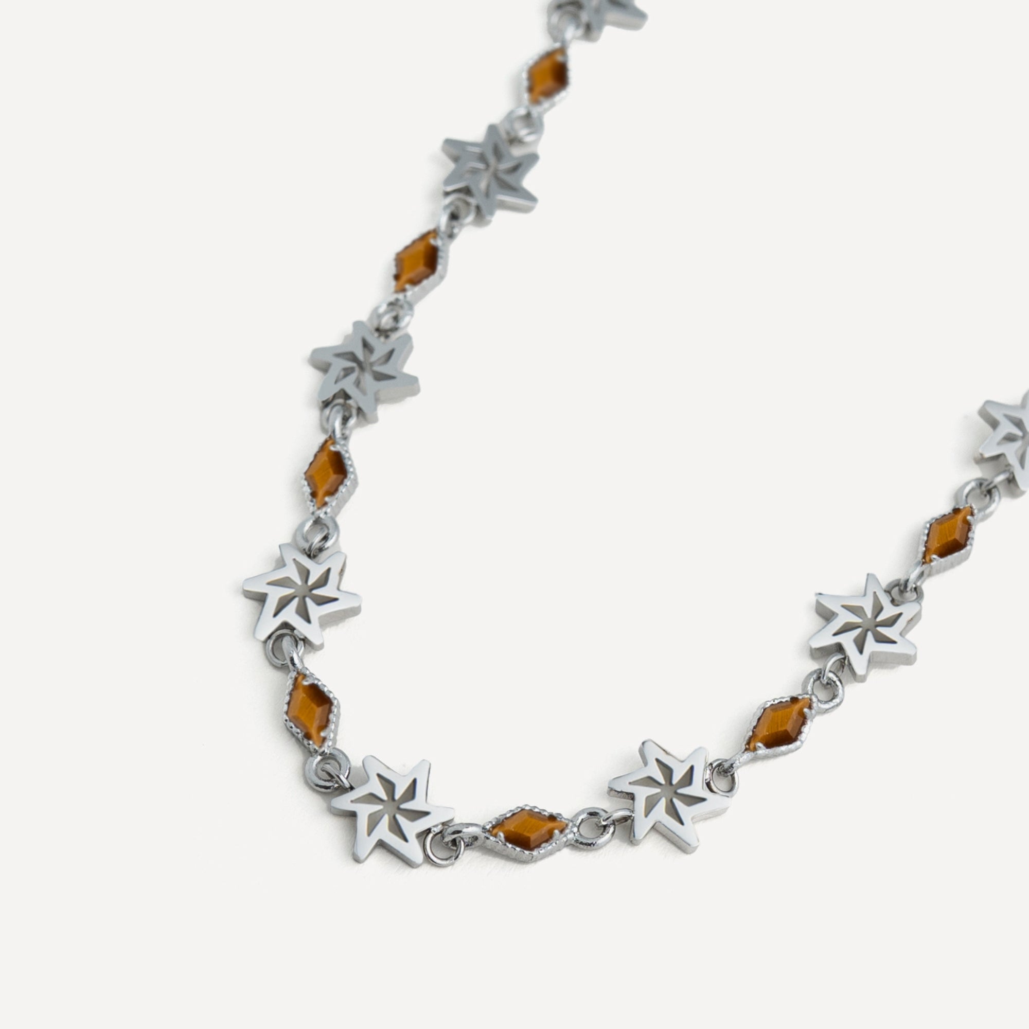 Silver bracelet with star-shaped links and amber-colored beads on a white background