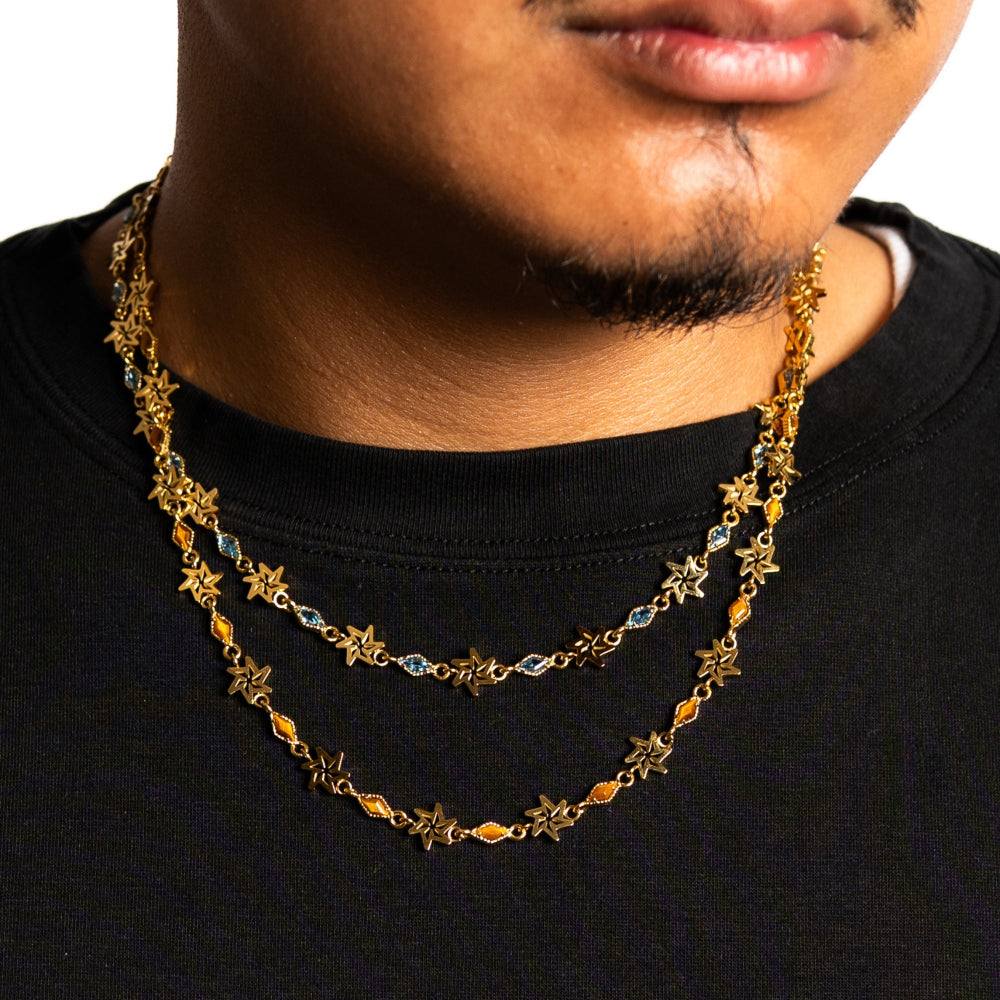 Close-up of a person wearing a gold chain necklace with star and bead details.