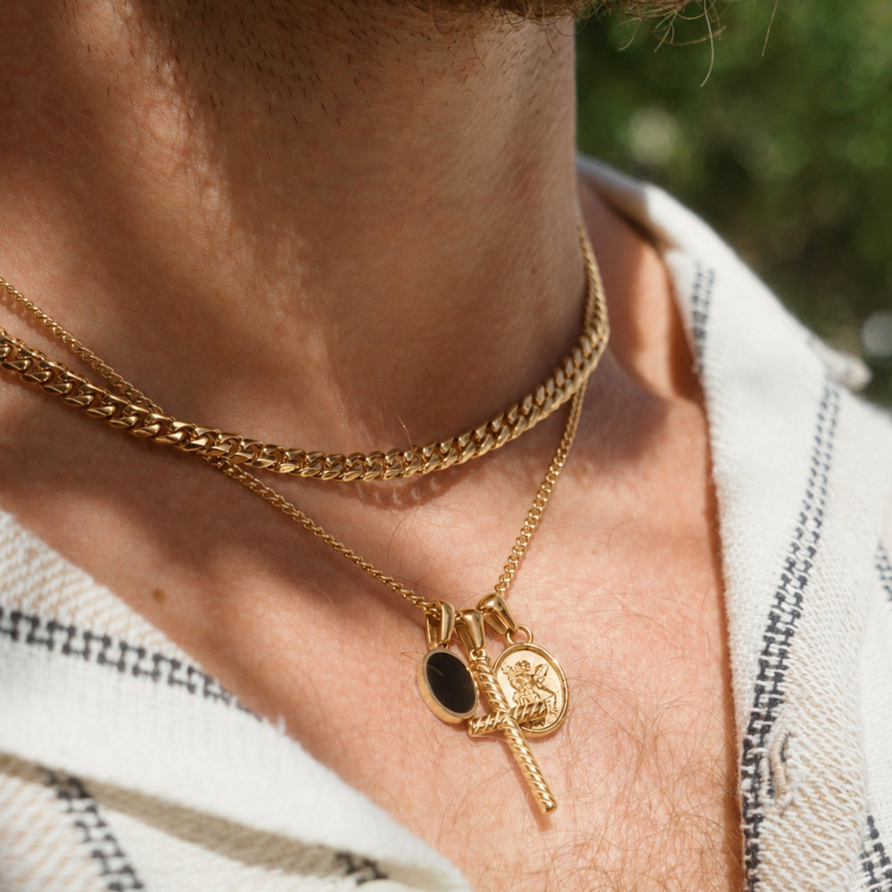 Close-up of a person wearing multiple gold necklaces with pendants.