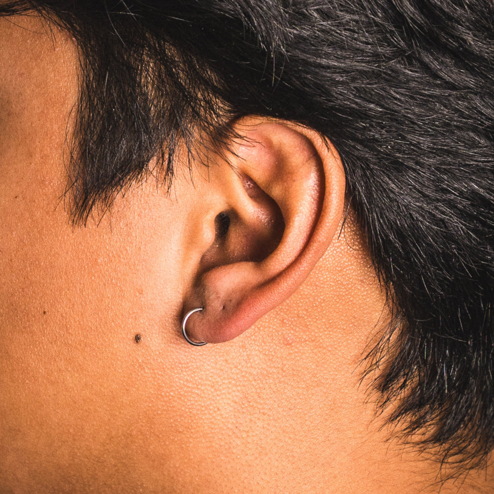 Close-up of an ear with a hoop earring and dark hair.