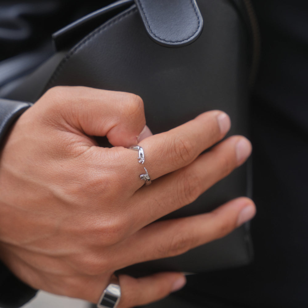 Close-up of a hand wearing two silver rings with a blurred background