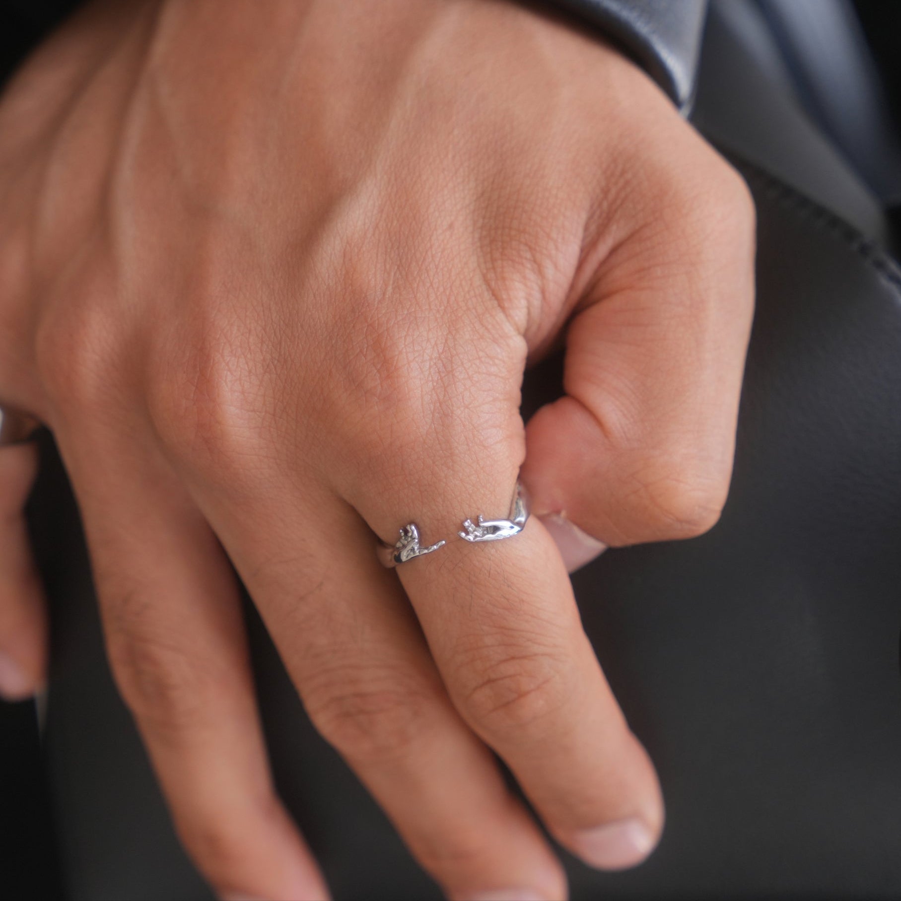 Close-up of a hand wearing a silver ring with a blurred background