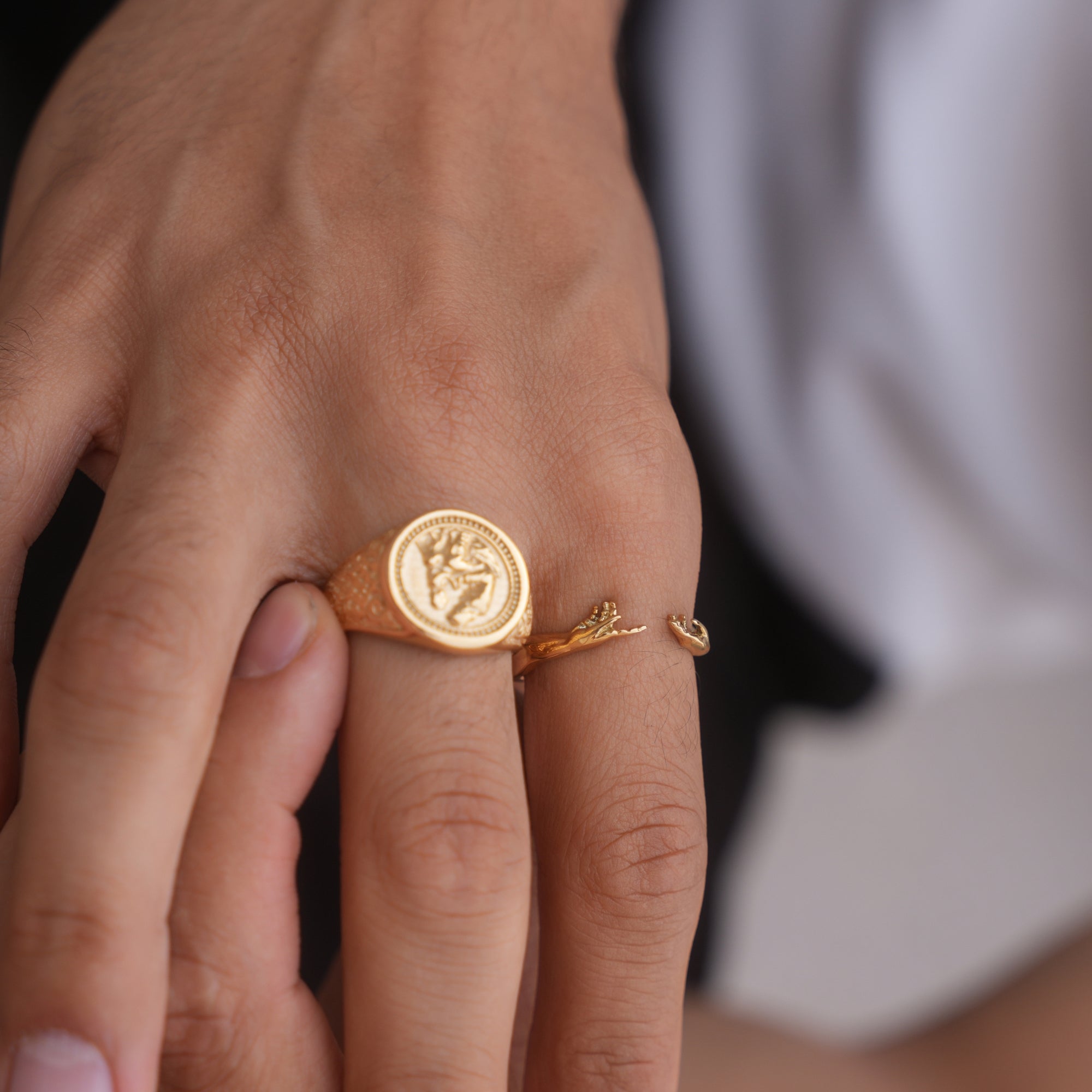 Gold ring with a circular design on a person's finger