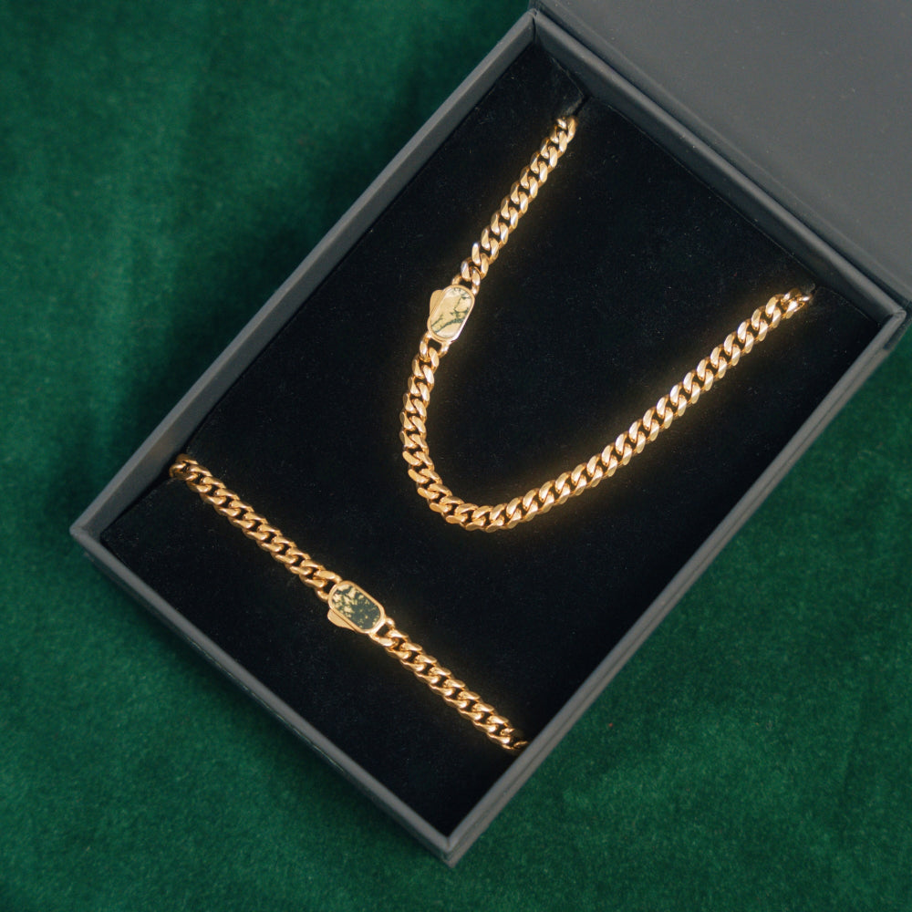 Gold chain necklace in a black box on a green surface