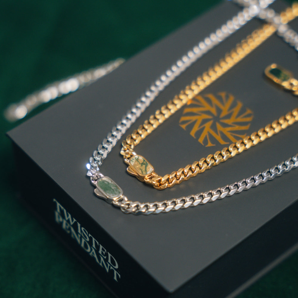 Gold, silver, and green chain necklaces on a black box with 'Twisted Pendant' branding.