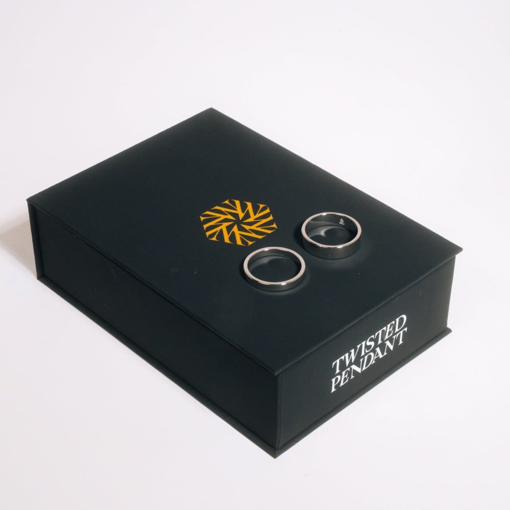 Black jewelry box with 'Twisted Pendant' branding and two silver rings on a white background