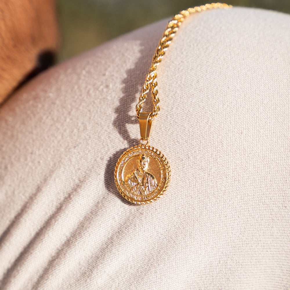 Gold necklace with a coin pendant on a textured surface