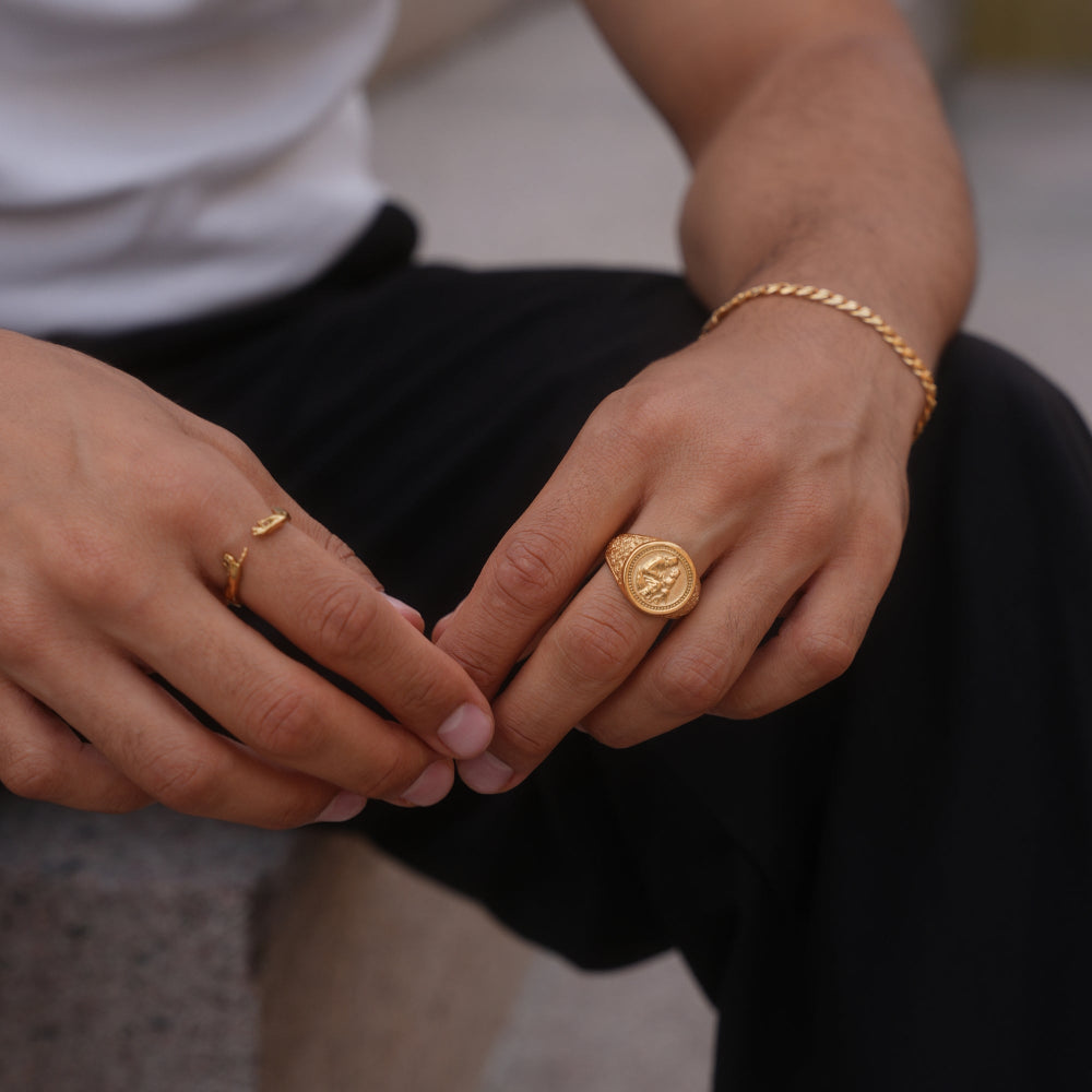Close-up of hands with gold rings and a bracelet on a blurred background