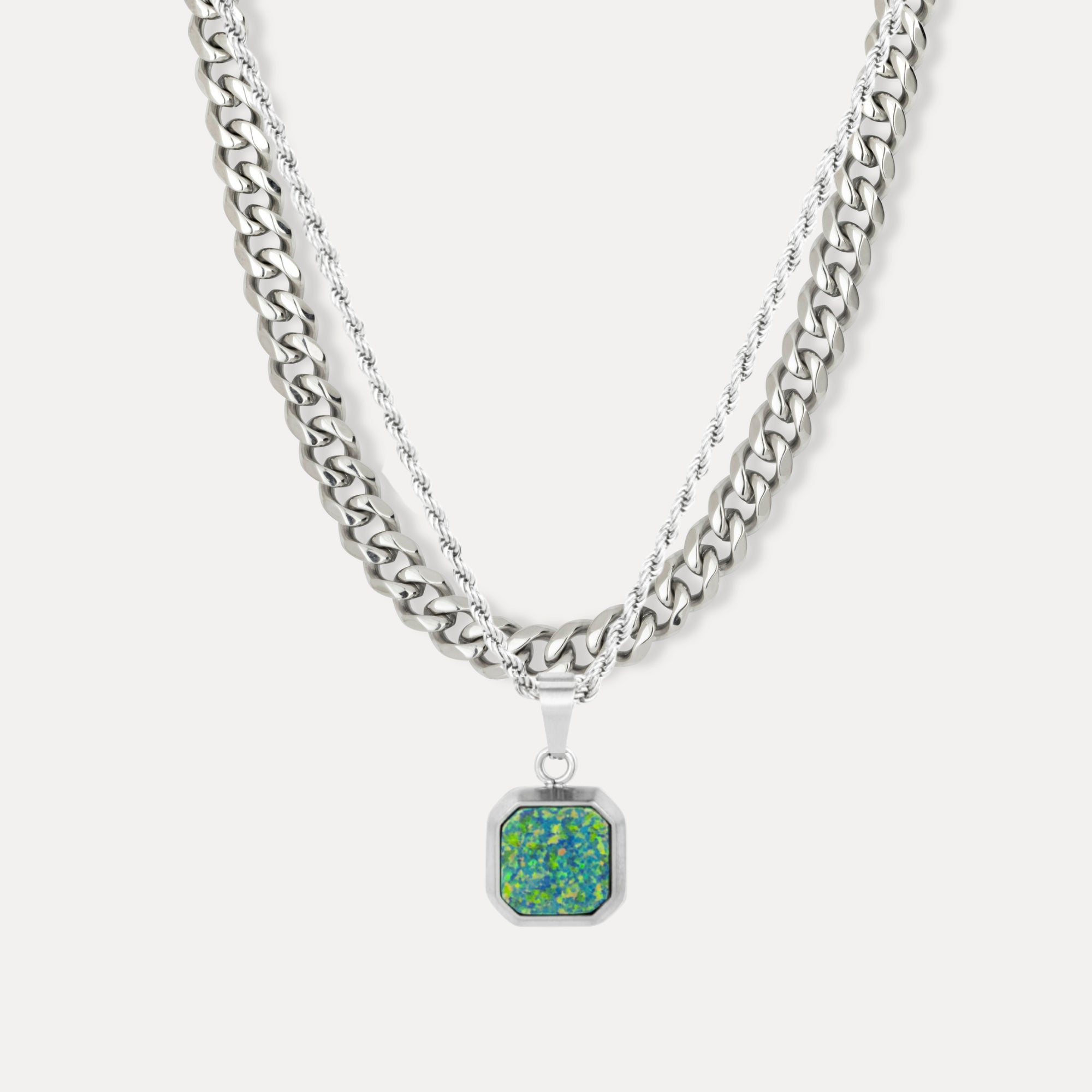 Silver chain necklace with a green pendant on a white background